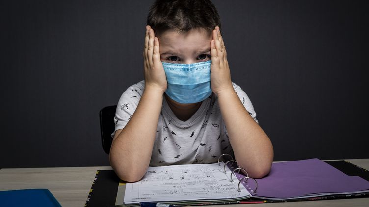 Un écolier masqué fait ses devoirs pendant le deuxième confinement en France le 31 octobre 2020. (MAXIME FRAISSE / HANS LUCAS / AFP)