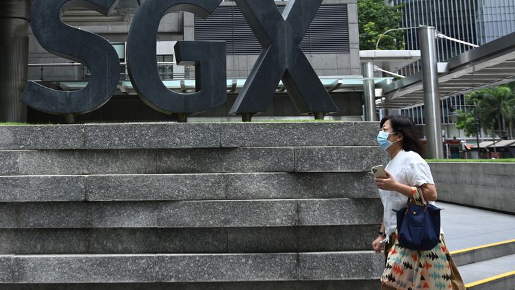 Une femme masquée passe devant la bourse de Singapour, le 7 avril 2020. (ROSLAN RAHMAN / AFP)